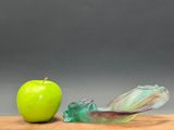 a green apple sitting next to an apple on a cutting board