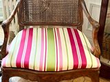 a wooden chair with a striped seat and a mirror in the background