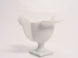 a white vase with a bird on it on a white surface