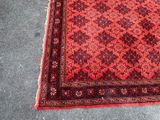 an oriental rug with a red and black design on a grey floor