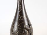 un vase noir orné de motifs dorés, posé sur un socle
