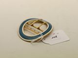 une photo d'une broche bleue et blanche à laquelle est accrochée une étiquette