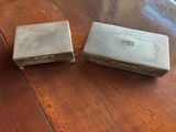 two silver boxes sitting on top of a wooden table next to each other