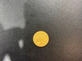 a yellow coin sitting on top of a black table next to a shadow of a person