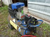a small air compressor sitting on the ground next to a bucket
