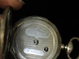 a person holding a silver pocket watch in their hand