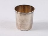 une tasse en argent posée sur une surface blanche