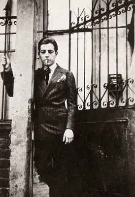 a black and white photo of a man standing in front of a gate