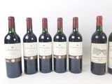 six bottles of wine are lined up in a row on a white surface