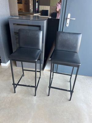 une paire de tabourets de bar en cuir noir placés devant un îlot de cuisine