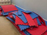 un tas de tapis rouges et bleus posés par terre dans une pièce