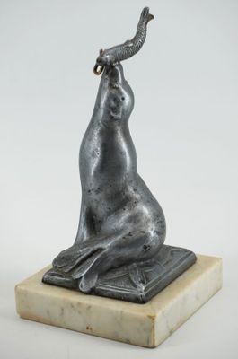 une statue représentant une chèvre assise sur un bloc de marbre