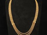 a gold chain necklace on a mannequin with a black background