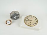 deux horloges et une montre posées sur une surface blanche