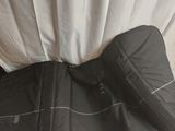 a black sleeping bag on the floor next to a white curtain