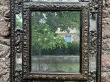 un miroir accroché à un mur de pierre, avec un arbre en arrière-plan
