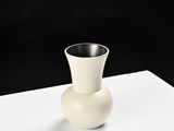 a white vase sitting on top of a piece of paper
