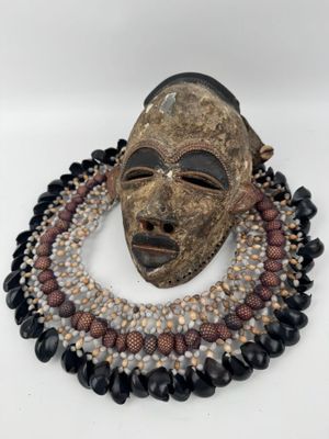 un gros plan d'un masque accroché à un collier orné de perles