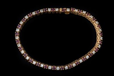un gros plan d'un bracelet en or et rubis sur fond noir