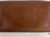 brown leather wallet with zipper on top of it sitting on a white surface
