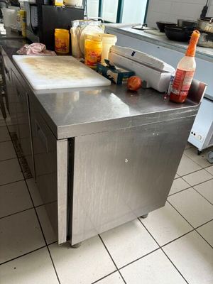 un plan de travail en acier inoxydable dans une cuisine professionnelle, sur lequel sont disposés de nombreux condiments