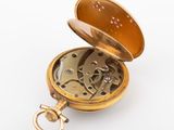 a gold pocket watch with a chain on a white surface