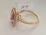a close up of a ring with a purple stone surrounded by diamonds