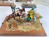 two figurines of people riding horses on display