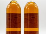two bottles of wine sitting next to each other on a white surface