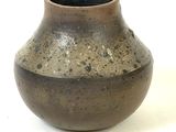 a brown vase that is sitting on a white surface