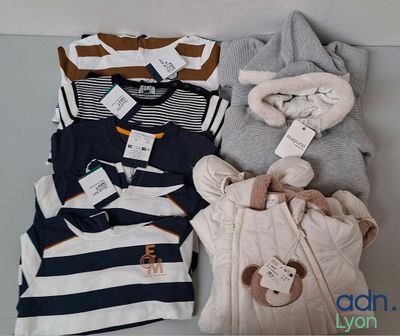 a pile of baby clothes on a shelf next to a stuffed animal