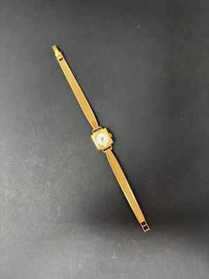 a gold watch on a black surface with a gold band