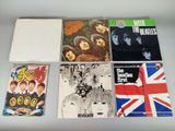 various beatles albums and cds are arranged on a table