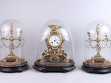 trois dômes en verre, chacun abritant une horloge, posés sur une table