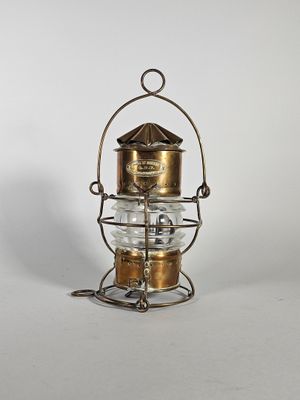 une lanterne ancienne en laiton et en verre posée sur un pied en métal