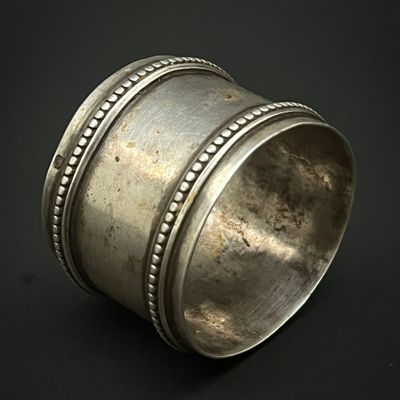 un rond de serviette ancien en argent, orné de bords perlés sur fond noir