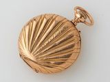 an antique gold pocket watch with a shell on the front