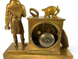 a bronze clock with a man standing next to it