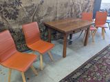 trois chaises orange et une table dans une pièce