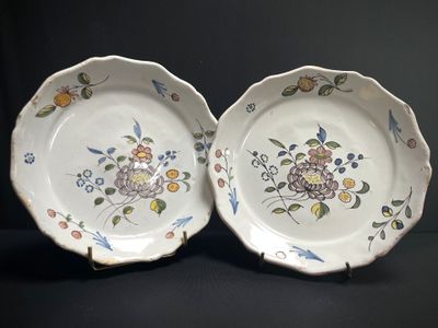 two plates with flowers and birds painted on them sitting on a table