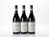 three bottles of red wine sitting on top of a white surface