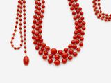 gros plan d'un collier de perles rouges sur fond blanc