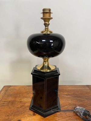 une photo d'une lampe noire et dorée posée sur une table en bois
