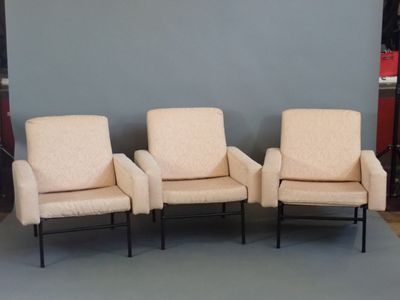 trois chaises beiges placées devant un mur gris