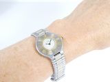 wrist of a woman with a watch on her wrist on a white surface