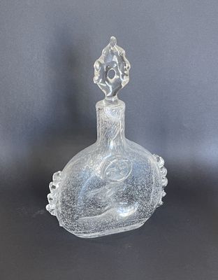une bouteille en verre transparent surmontée d'un oiseau