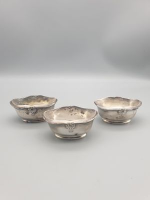 un ensemble de trois bols plaqués argent posés sur un support blanc
