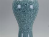 un vase bleu posé sur un socle en bois, sur fond blanc