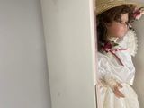 a doll that is sitting in the corner of a cabinet