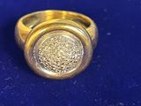 une bague en or sertie d'une pierre, posée sur un fond bleu